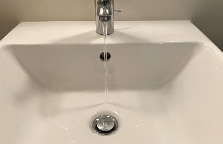 Tap water running into a bathroom sink.